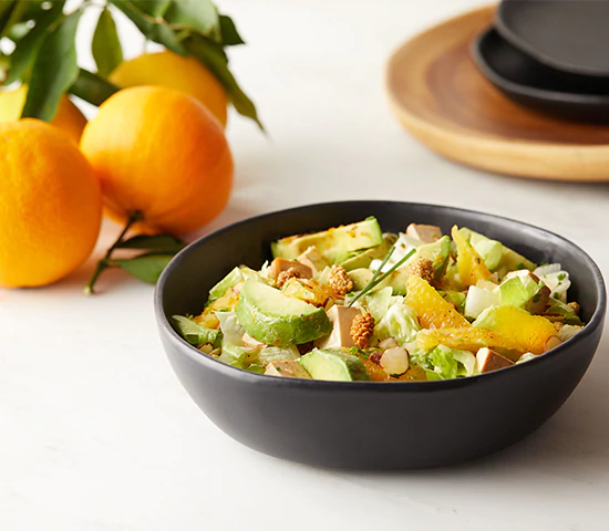 A bowl filled with a citrus avocado almond salad topped with Navitas Organics Mulberries