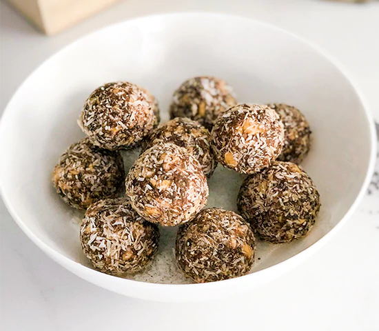 White bowl with rolled energy bites coated in coconut and made with Navitas Organics Chia Seeds
