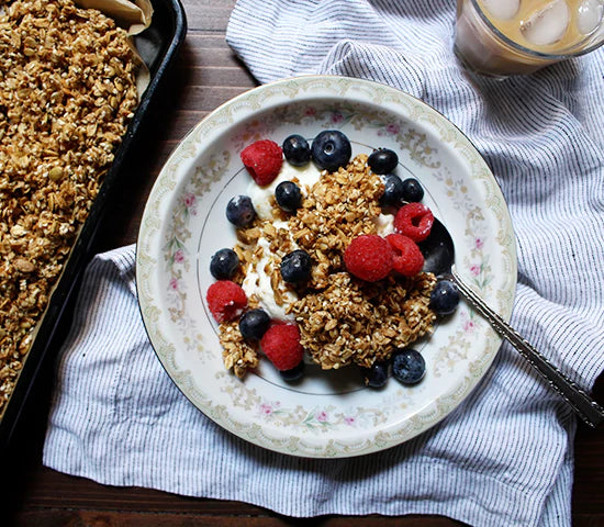 Bowl of pumpkin hemp granola topped with blueberries and raspberries