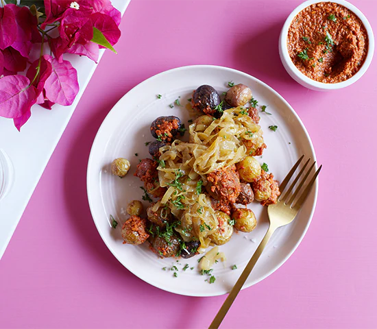 Plate of fingerling potatoes topped with a superfood Romesco sauce and caramalized onions