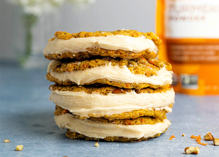 A stack of carrot cake cookie sandwiches made with Navitas Organics Turmeric Powder and Chia Seeds on a counter.