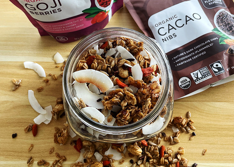 A mason jar filled with homemade granola made with Navitas Organics Cashew Nuts, Maca Powder, Cacao Nibs and Goji Berries.