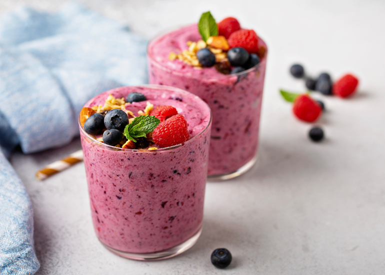 Two glasses filled with smoothies made with antioxidant-rich superfoods and berries including Navitas Organics Acai Powder