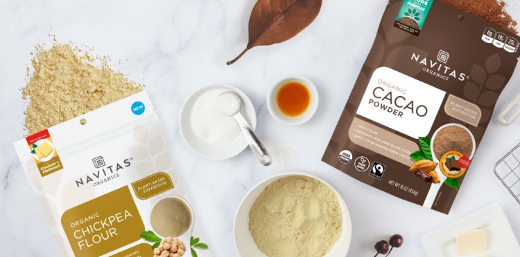 Navitas Organics Chickpea Flour and Cacao Powder on a kitchen counter with other baking tools.